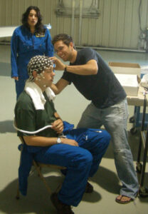 Karl, a pilot and experimental subject, prepares to have his mind read by EEG, as researcher Greg makes sure the electrodes make good contact with the skin. (Don’t ask what that expression on my face is all about, I’ve no idea…)